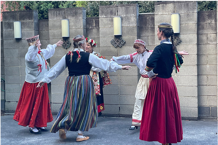 five folk dancers dance in a circle