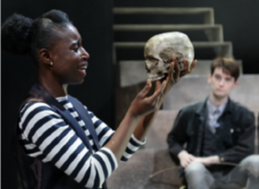woman holding skull with male actor in background