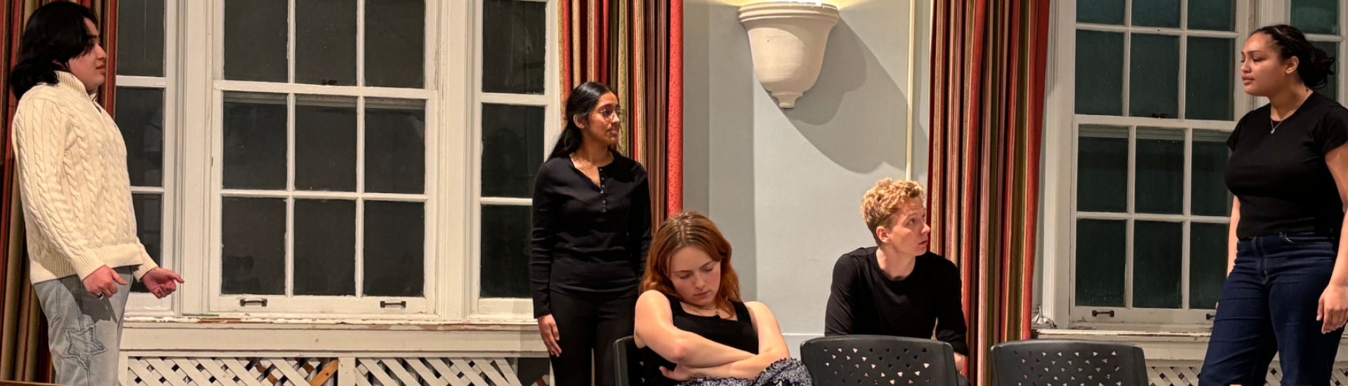Five actors on stage two are seated and three are standing in a scene from Chekov's Cherry Orchard